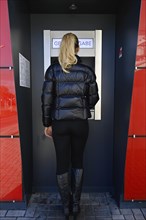 Woman standing in front of an ATM at a savings bank