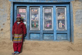 A local woman is standing in front of the window of her shop