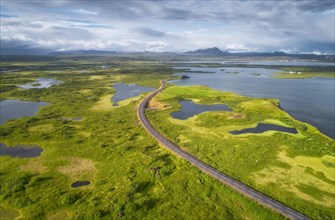 Aerial view of road through green landscape with volcanic crater