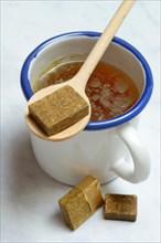 Cup with bouillon broth and bouillon cubes on a wooden spoon