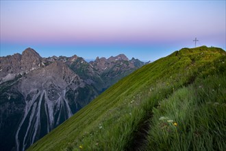 Small mountain trail with flower meadow and summit of the Uentschenspitze at sunrise