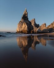 Marked rocks at Praia da Ursa beach with reflection