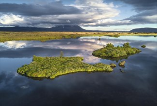 Green islands and dramatic clouds are reflected in Lake Myvatn