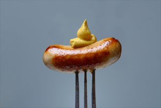 Chipolata sausages with mustard on fork