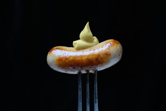 Chipolata sausages with mustard on fork