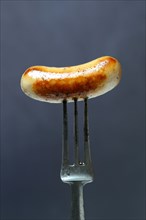 Chipolata sausages on fork
