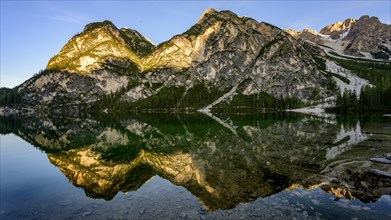 Mountains in the evening light are reflected in Lake Prags Lake