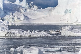 A Fisher boat is sailing between colossal icebergs