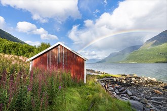 Boat hut with rainbow at the fjord