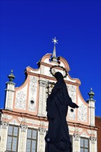 Statue of the Virgin Mary with a halo in front of a decorative facade