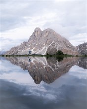 Peitlerkofel with reflection in small lake and jumping person