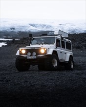 White Land Rover in front of a glacier