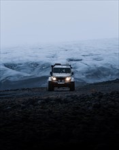 White Land Rover Jeep in front of a glacier
