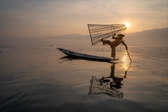 Traditional fisherman posing standing on his small boat in front of sunrise