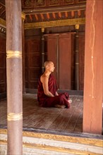 Buddhist monk with red robe meditating in a pagoda