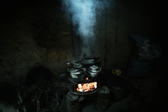 Teapots with milk tea on an oven with blazing embers