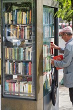 Man with books and public bookcase on the pavement of Luegallee in the Oberkassel district
