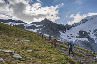 Hikers in front of snow-covered mountain peaks