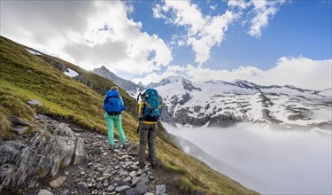 Hikers in front of snow-covered mountain peaks