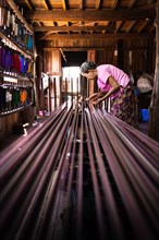 Woman pulling up colourful threads on loom