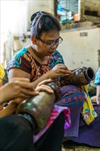 Sitting man working on a traditional vase with lacquer art from Bagan