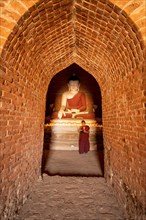 Buddhist young monk in red robe praying standing in a temple