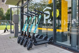Parked e-scooters of the company Tier in front of the entrance to a public parking garage