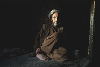 Shopkeeper sitting in the semi-darkness on the floor of his shop