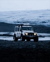 White Land Rover Jeep in front of a glacier