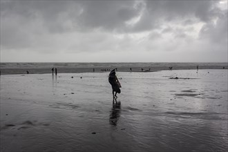 Bathers on the beach from Cox's Bazaar to monsoon rain