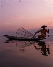A traditional fisherman sits with a lamp on his small boat