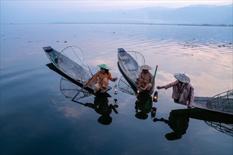 Three traditional fishermen sitting with lamps on their small boats