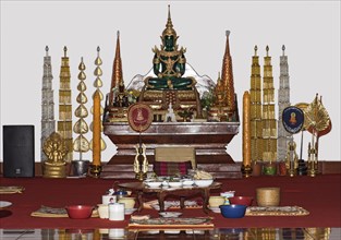 Donated food for monks in front of a small altar with a replica of the Emerald Buddha in meditation pose