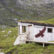 Simple wooden hut in the mountains with a picture of an eagle