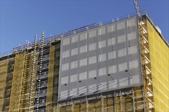 Facade with scaffolding and yellow cladding