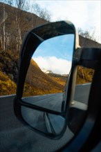 View through campervan mirror into autumnal fjord landscape