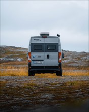 Campervan with rear view standing on parking lot near Kafjord