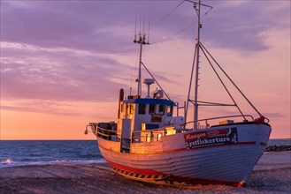 Fishing boat on the beach at sunset