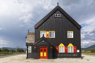 Black wooden house with red-yellow door and red-yellow shutters