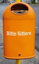 Funny orange garbage can with the inscription Bitte fuetern