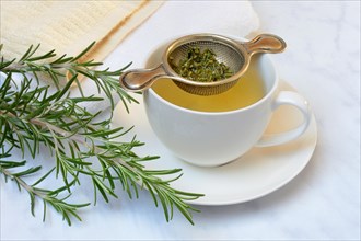 A cup of rosemary tea with tea strainer