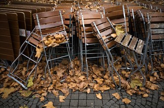 Tables and chairs of a closed beer garden in autumn leaves