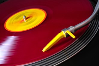 Red vinyl on a record player with yellow pickup