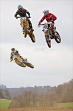 Three motocross machines in the air at the race