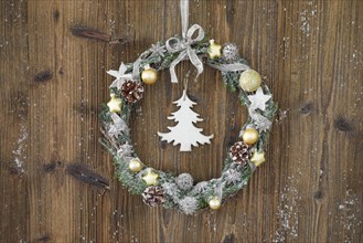Christmas wreath on brown wooden wall with fir tree