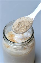 Tigernut flour in spoon and glass yoghurt