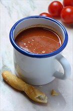 Tomato soup in cup with breadstick and tomatoes