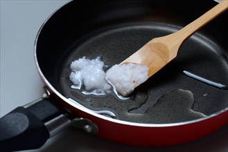 Coconut oil with bamboo spatula in frying pan