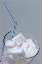 Sugar cubes in drinking glass with straw