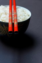 Boiled rice in bowl with chopsticks
